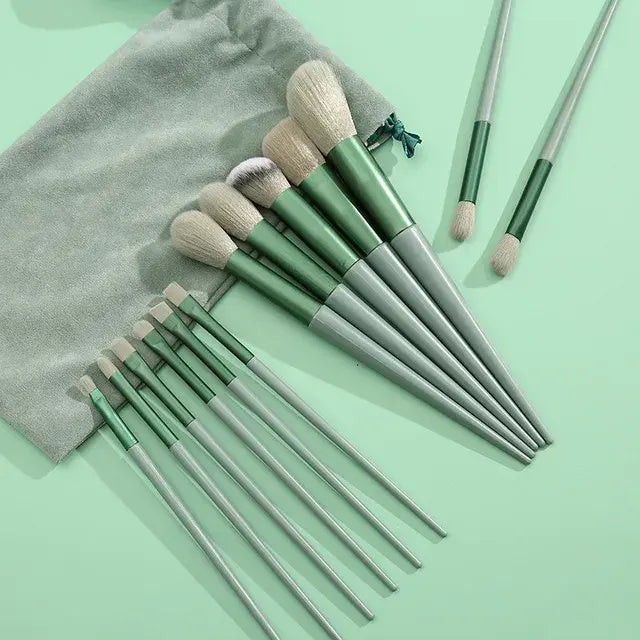 Set of green makeup brushes with a gray pouch on a light green background