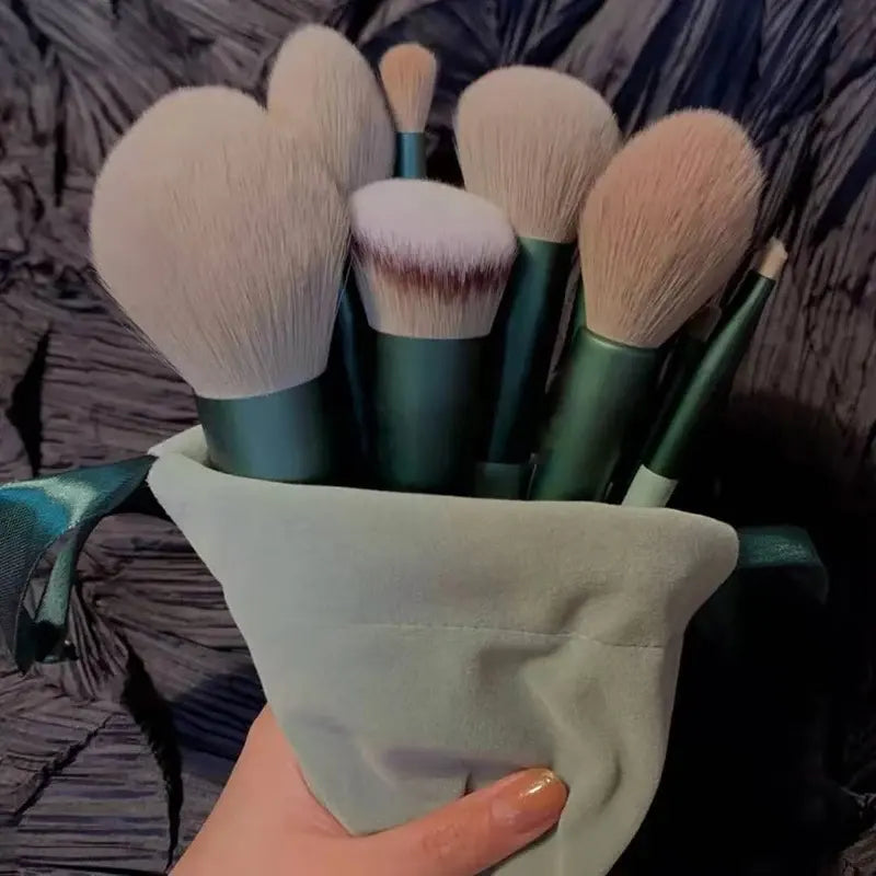 Set of makeup brushes in a green holder held by a hand against a textured background